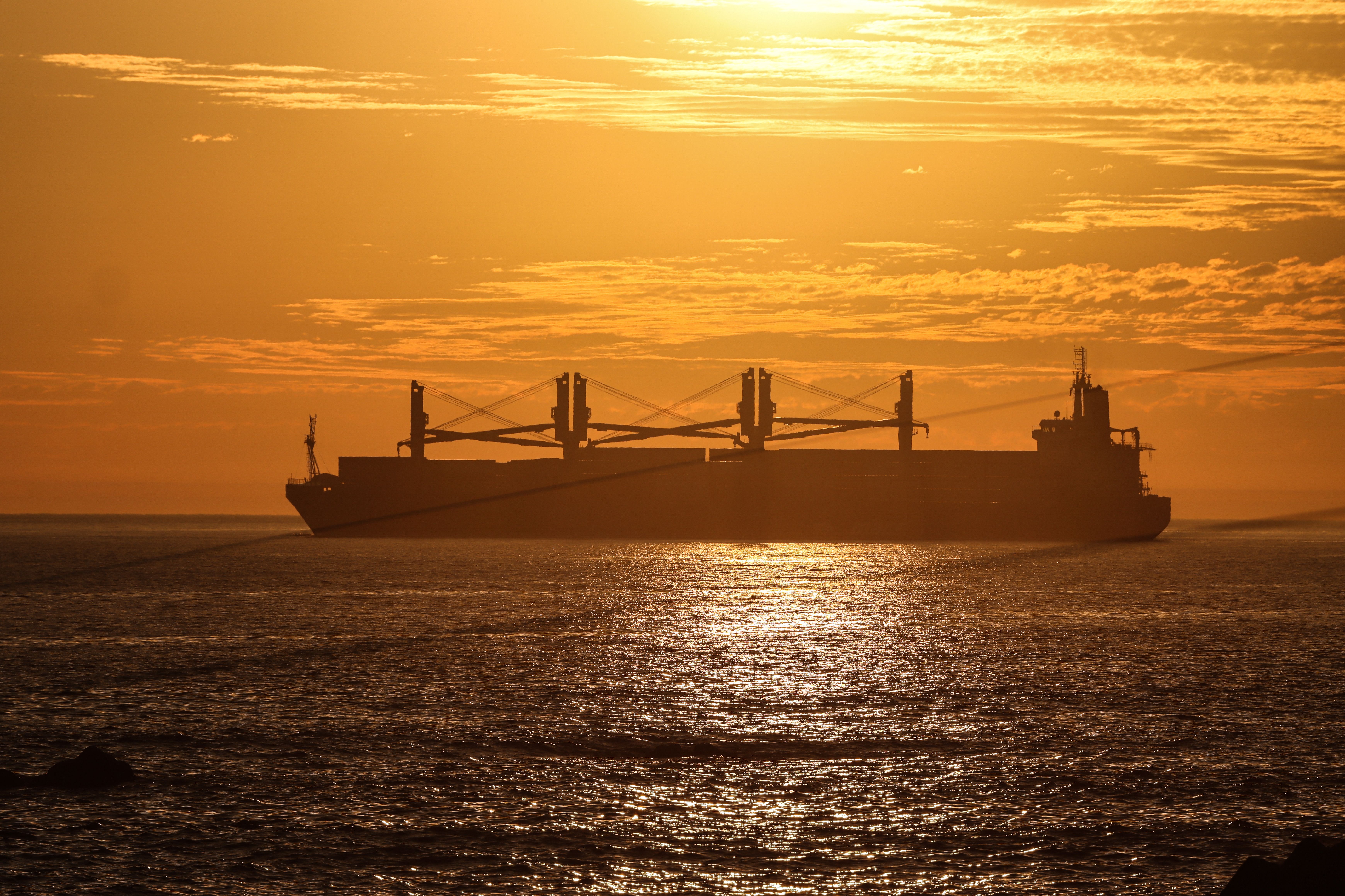 Silhouet van een bulkcarrier tegen de zonsondergang op zee