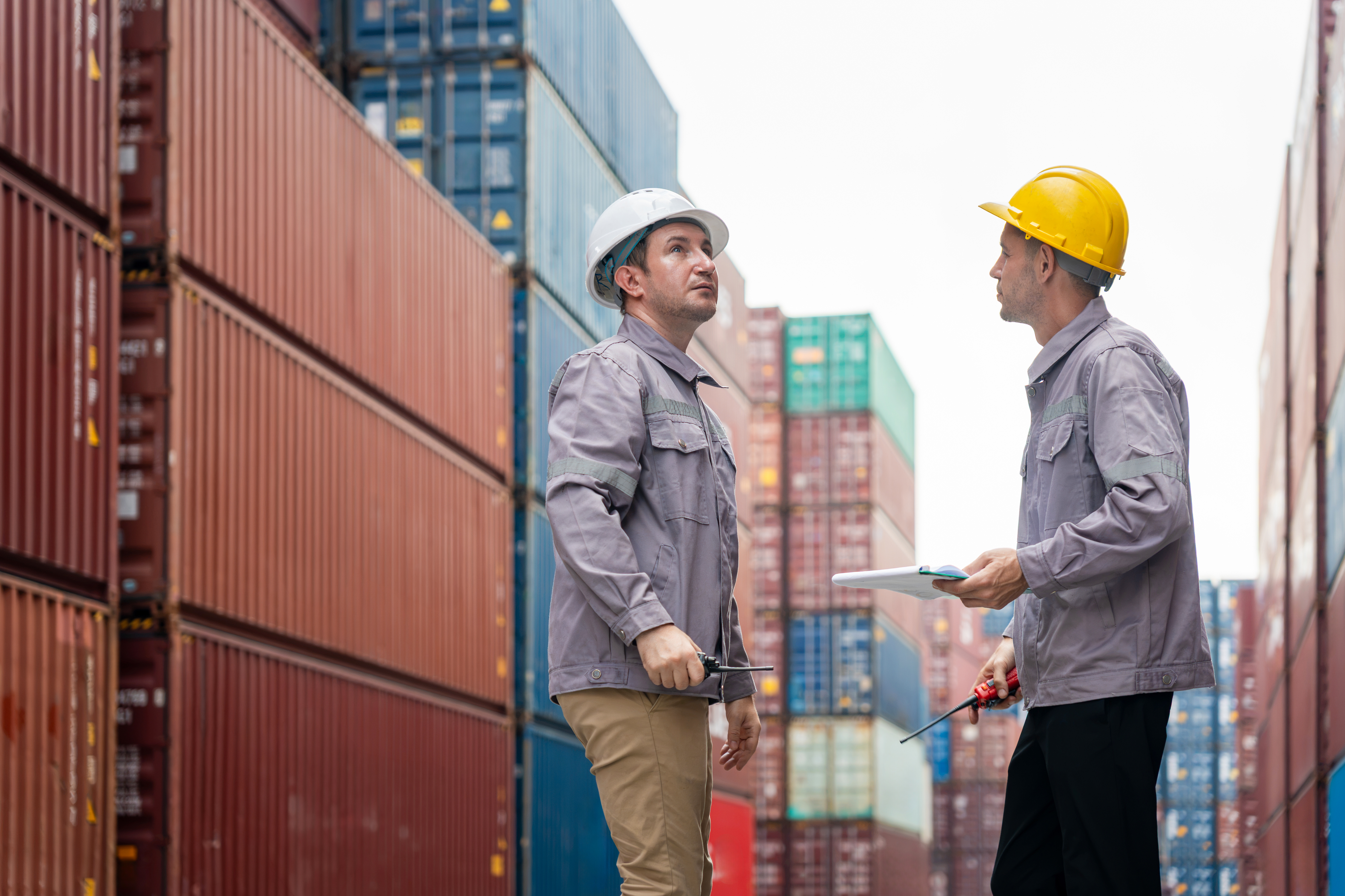 Twee terminalingenieurs die tussen gestapelde containers een checklist doornemen